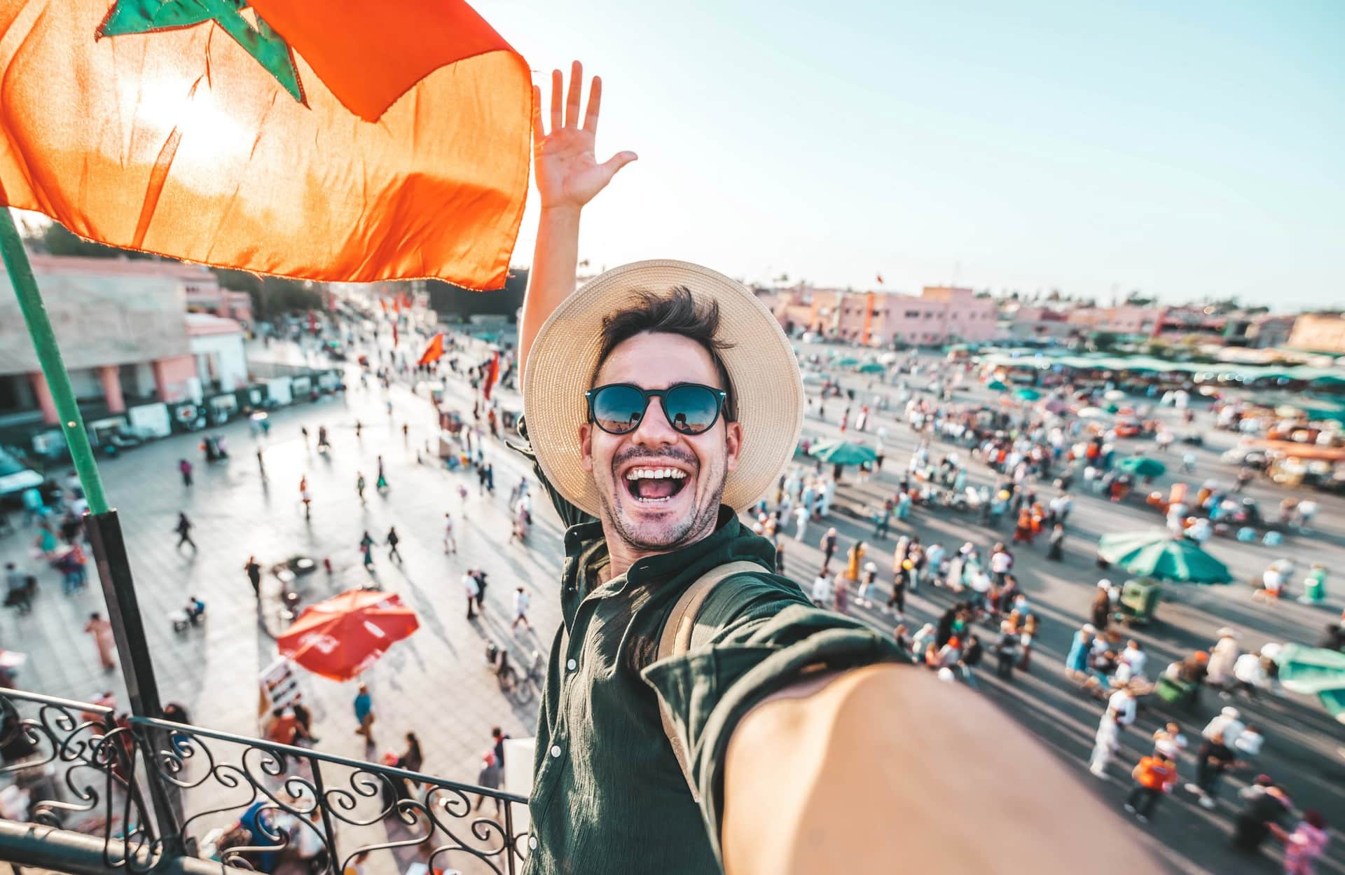 Turista haciendo selfie en terraza con vistas a la plaza Jemaa el-Fna de Marrakech llena de gente