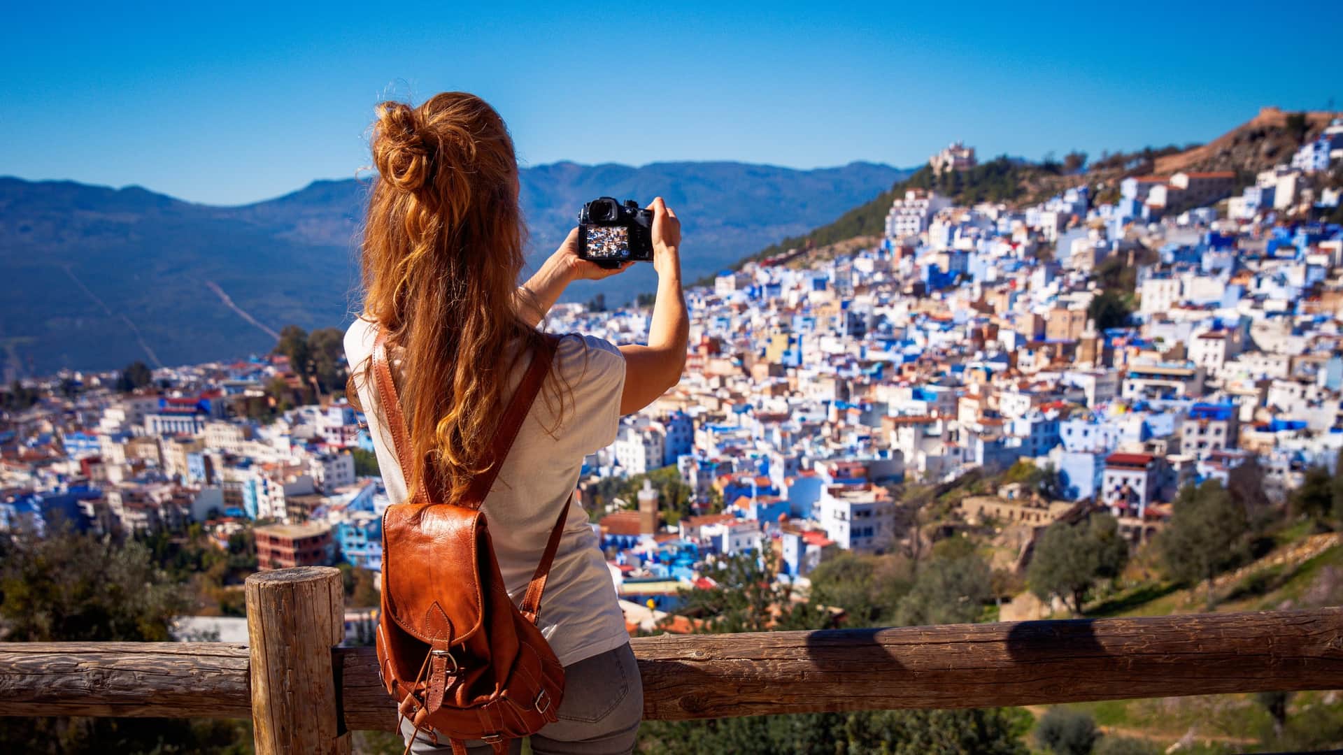 Viajera fotografiando el panorama azul de Chefchaouen desde un mirador en las montañas del Rif, Marruecos