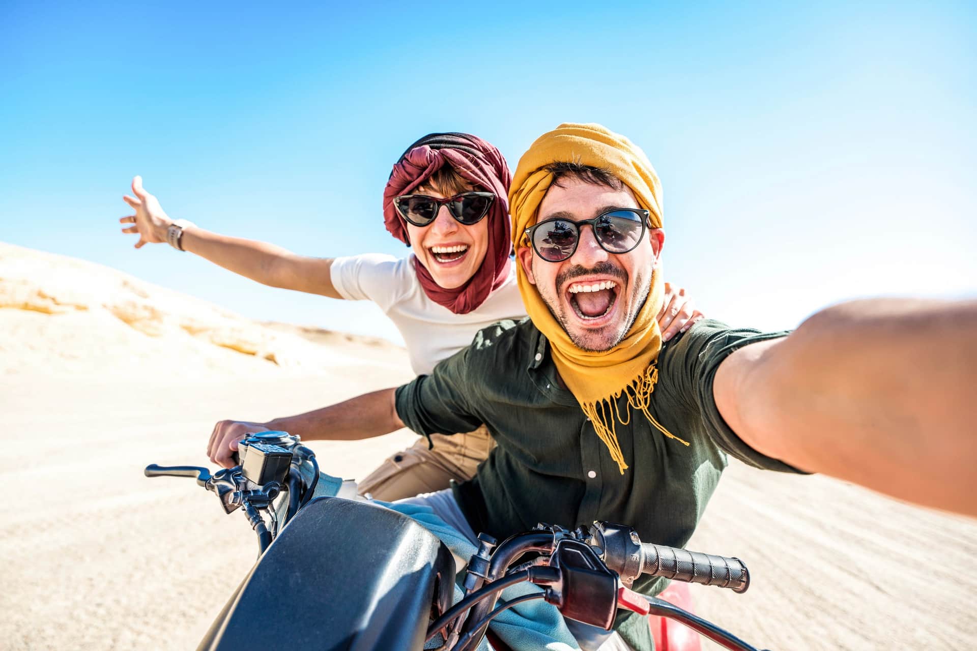 Pareja de viajeros en quad por las dunas del desierto del Sahara en Marruecos con turbantes bereberes