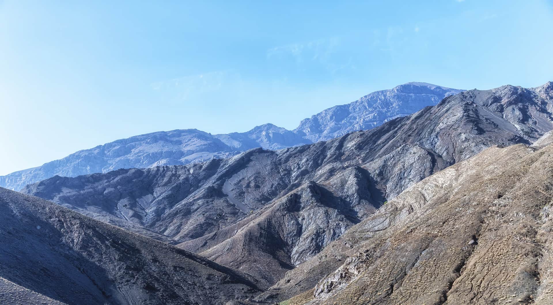 Paisaje árido del Alto Atlas marroquí con crestas rocosas escalonadas bajo cielo azul despejado