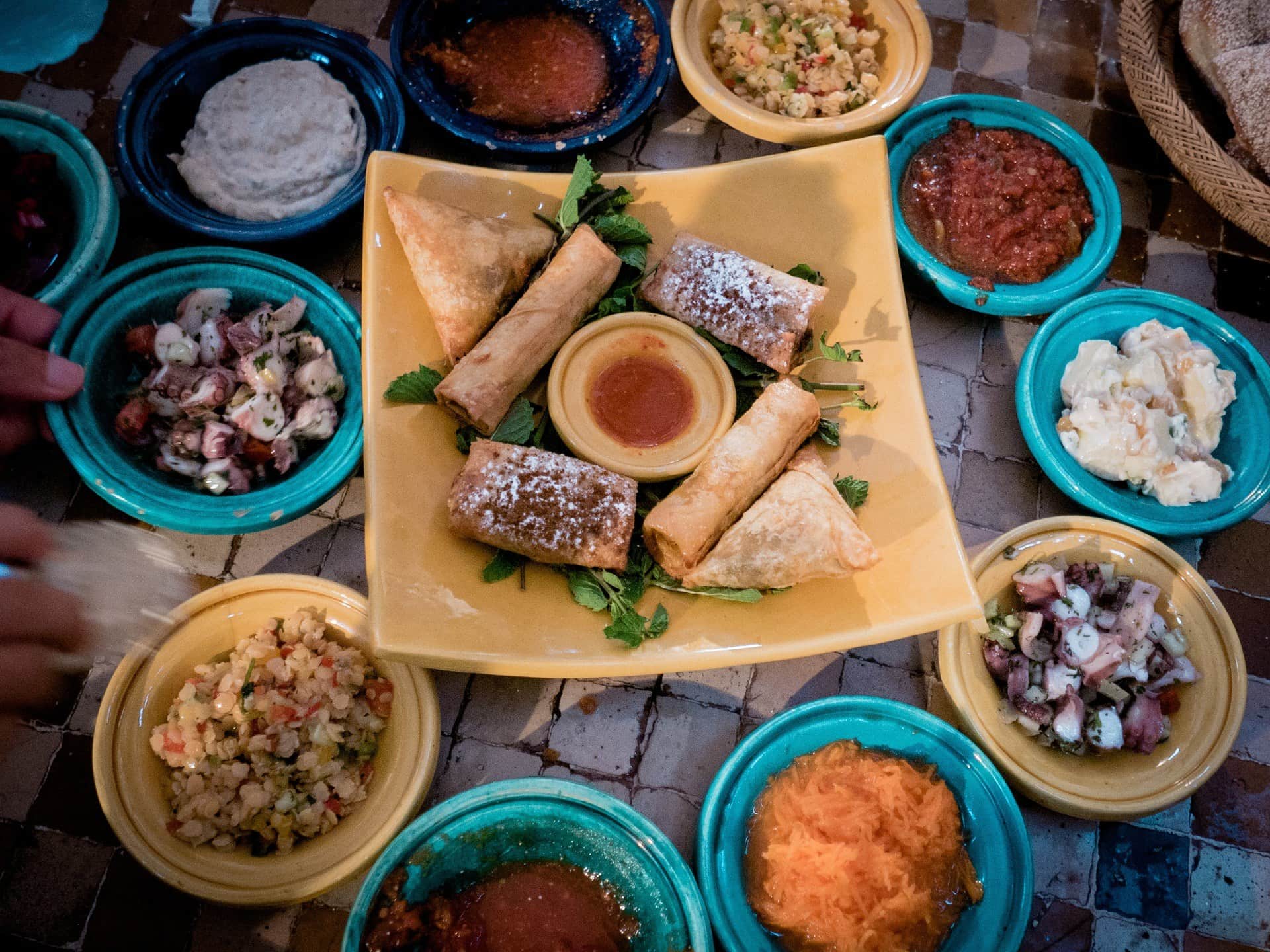 Entrantes típicos marroquíes con briouats, cigares de hojaldre y ensaladas variadas servidos en cuencos de cerámica artesanal