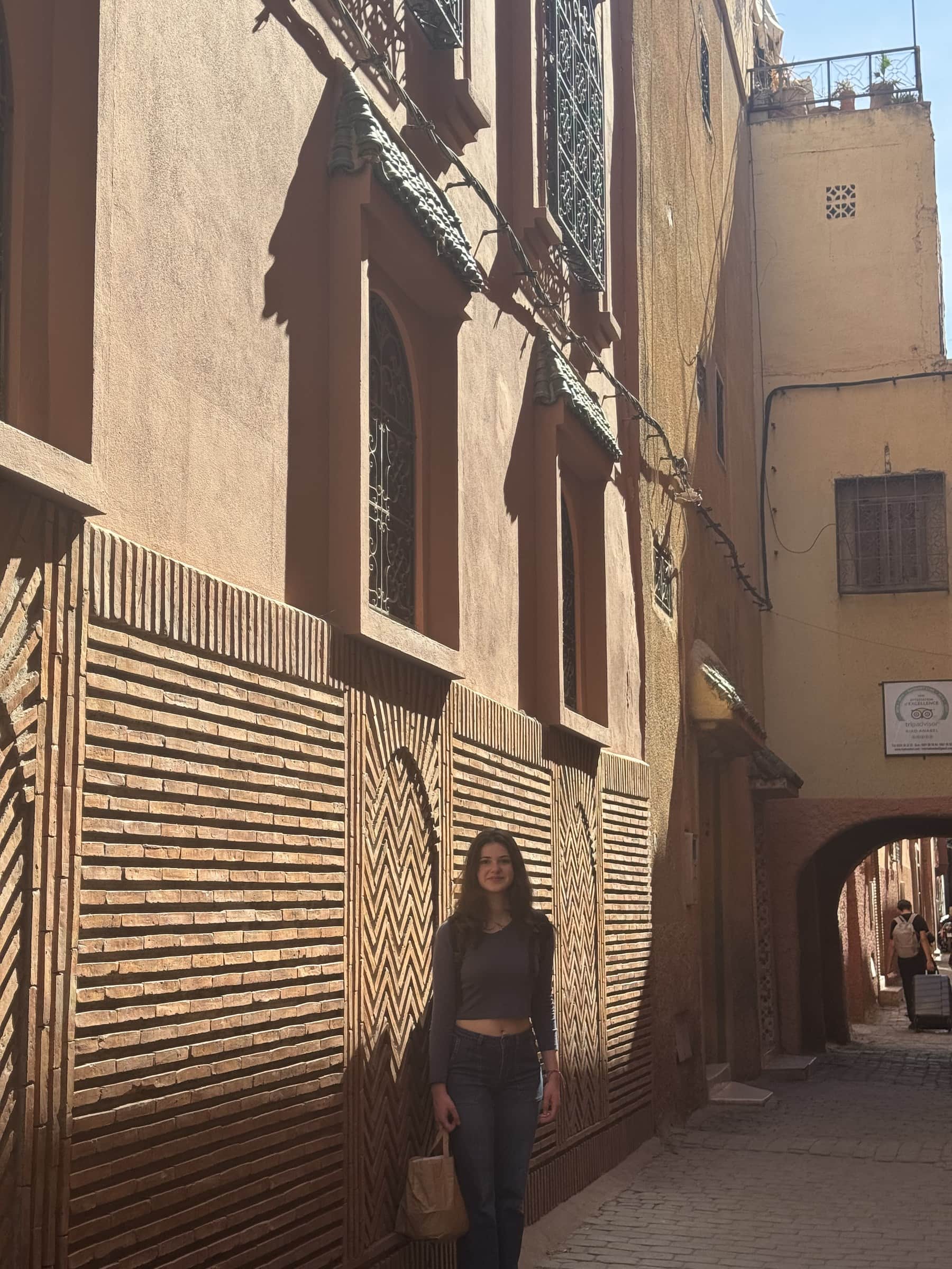 Viajera en callejón de la medina de Marrakech con pared de ladrillos en patrón geométrico tradicional