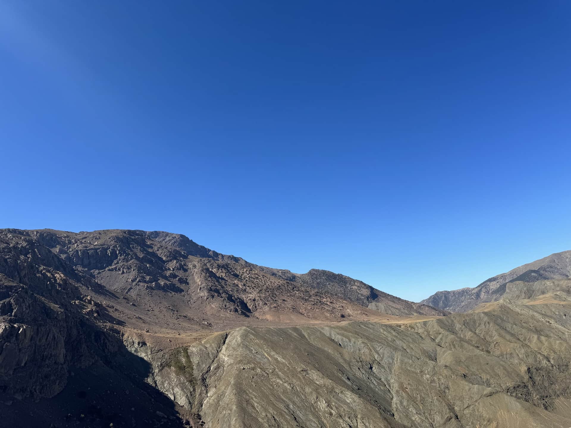 Paisaje árido del Alto Atlas marroquí con cumbres rocosas y cielo azul despejado