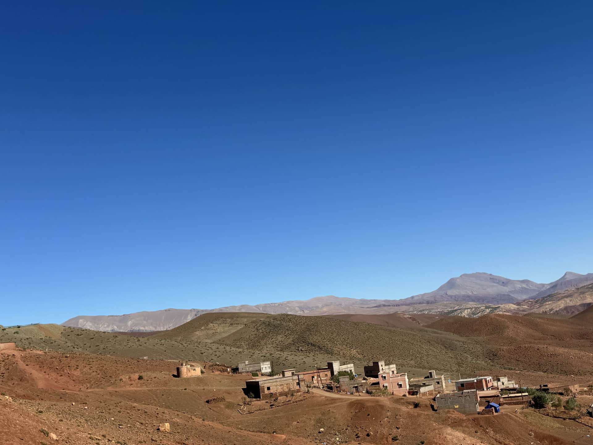 Aldea bereber en el Alto Atlas marroquí con casas de barro y montañas áridas bajo cielo azul intenso