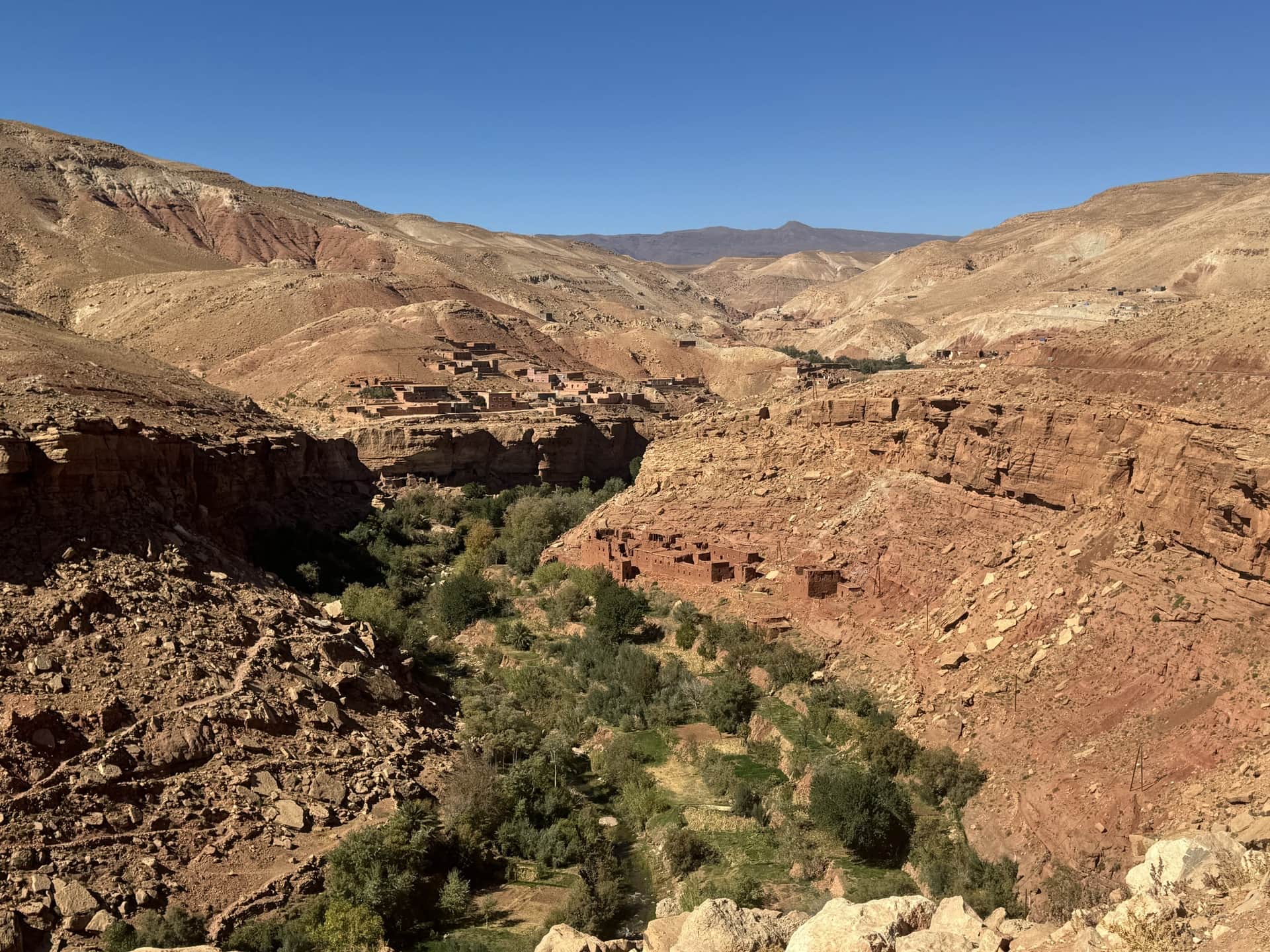 Valle del Dadés con aldea bereber de barro rojo entre acantilados ocres y vegetación verde, sur de Marruecos