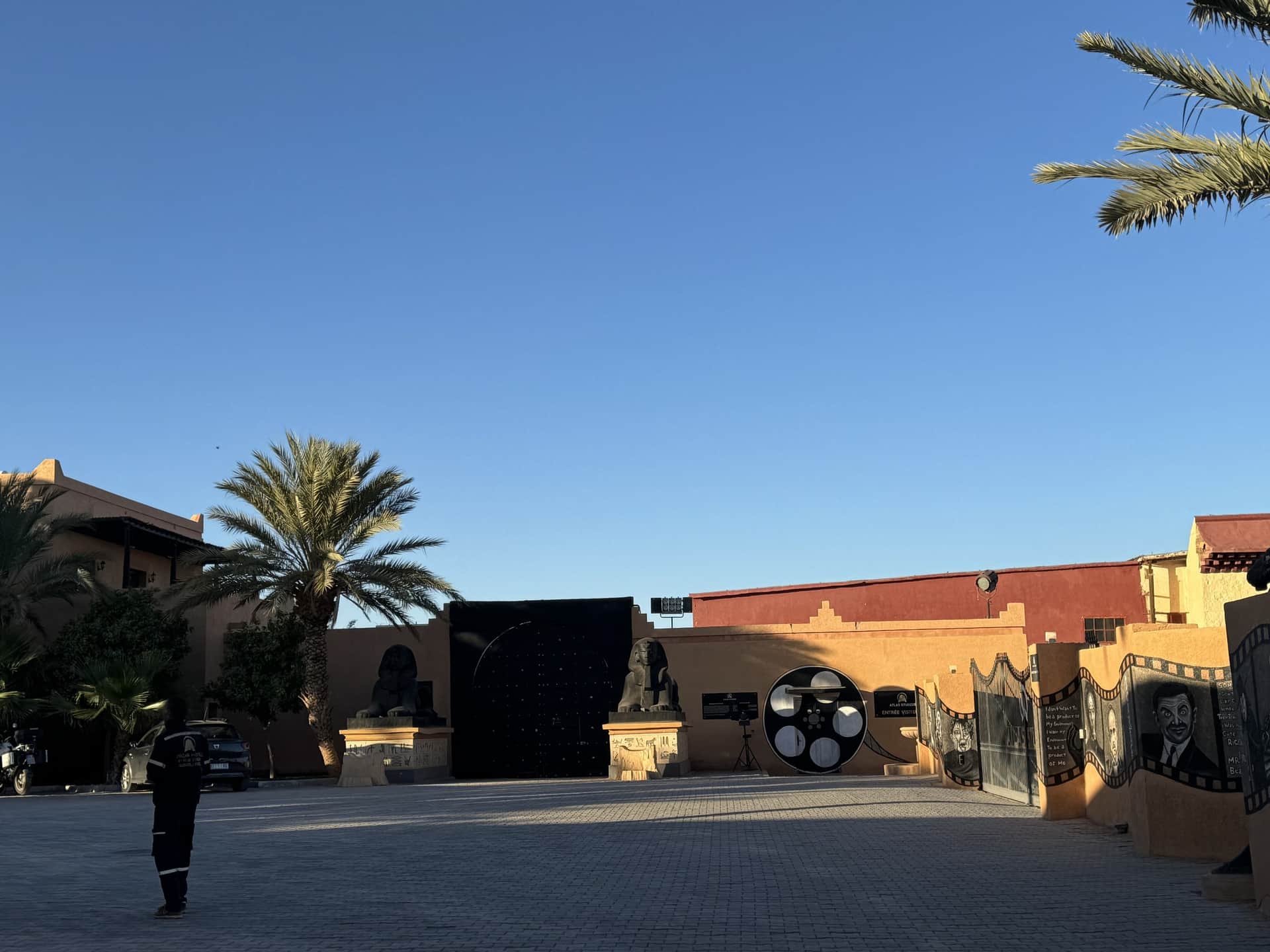 Entrada a los Atlas Studios de Ouarzazate con decoraciones de cine y palmeras bajo cielo azul