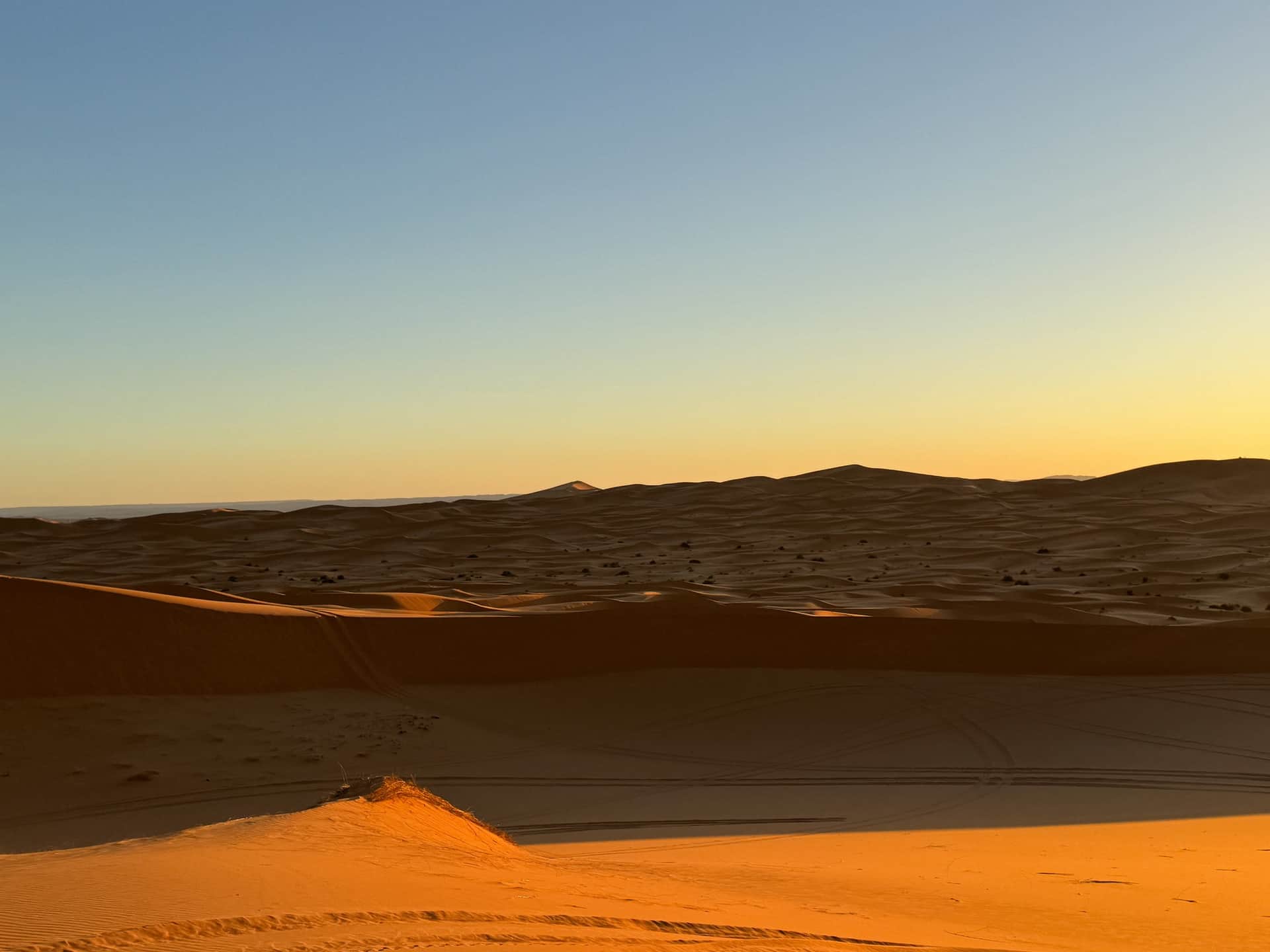 Dunas doradas del Erg Chebbi en Merzouga al atardecer con cielo degradado azul y naranja, Sahara marroquí