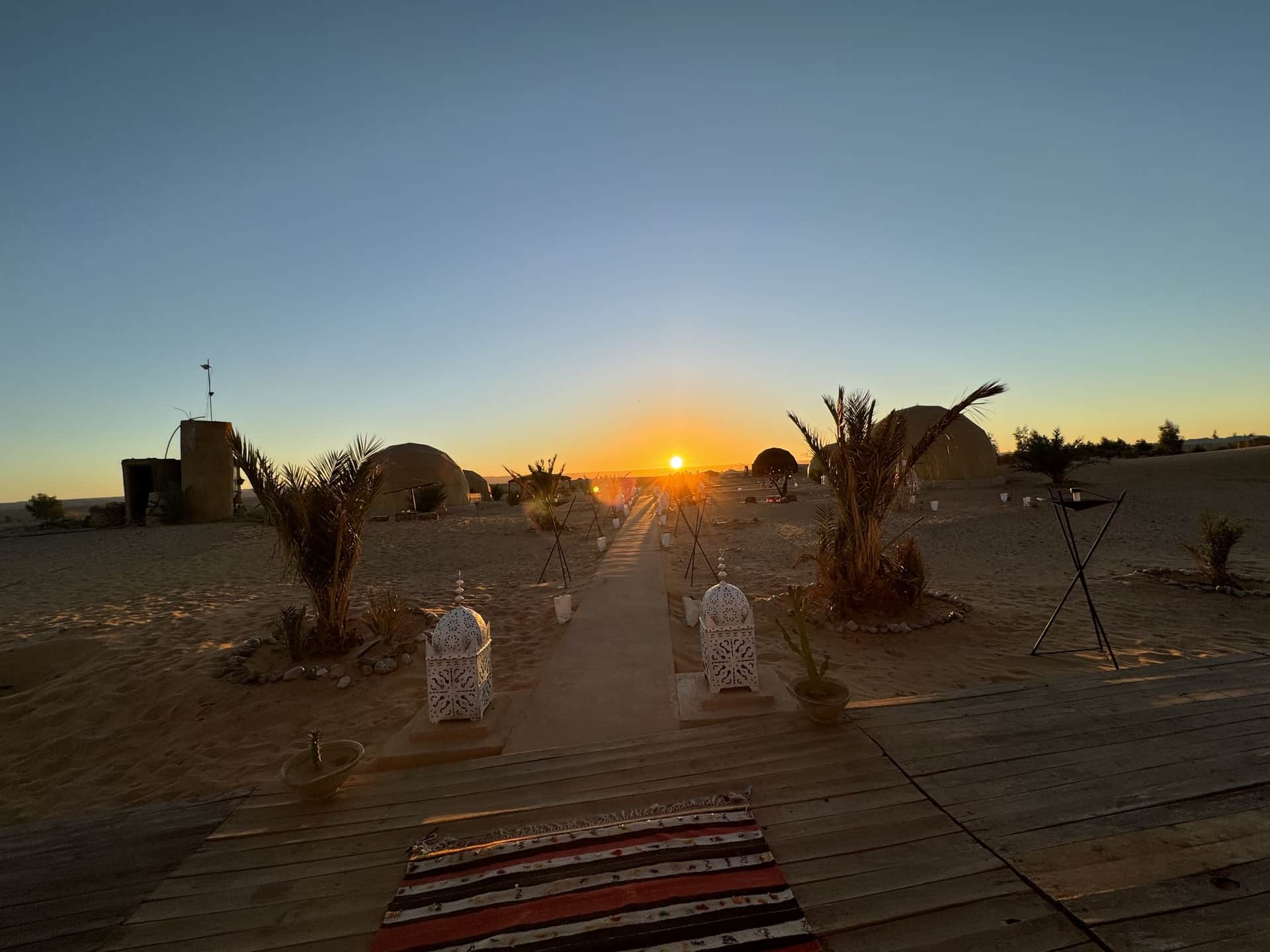 Campamento de lujo en el desierto de Merzouga al atardecer con linternas marroquíes y tiendas jaima