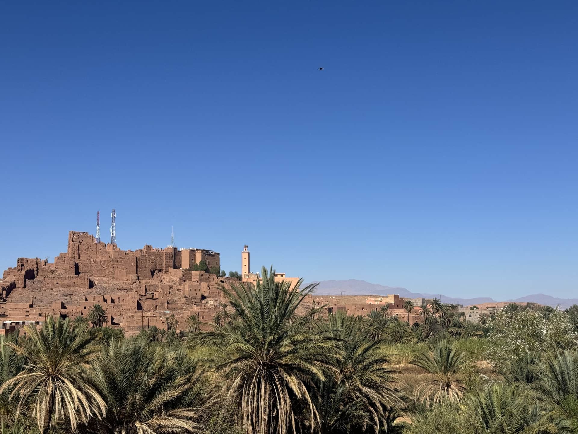 Kasbah de barro en ruinas sobre palmeral en Ouarzazate, Marruecos, bajo cielo azul intenso