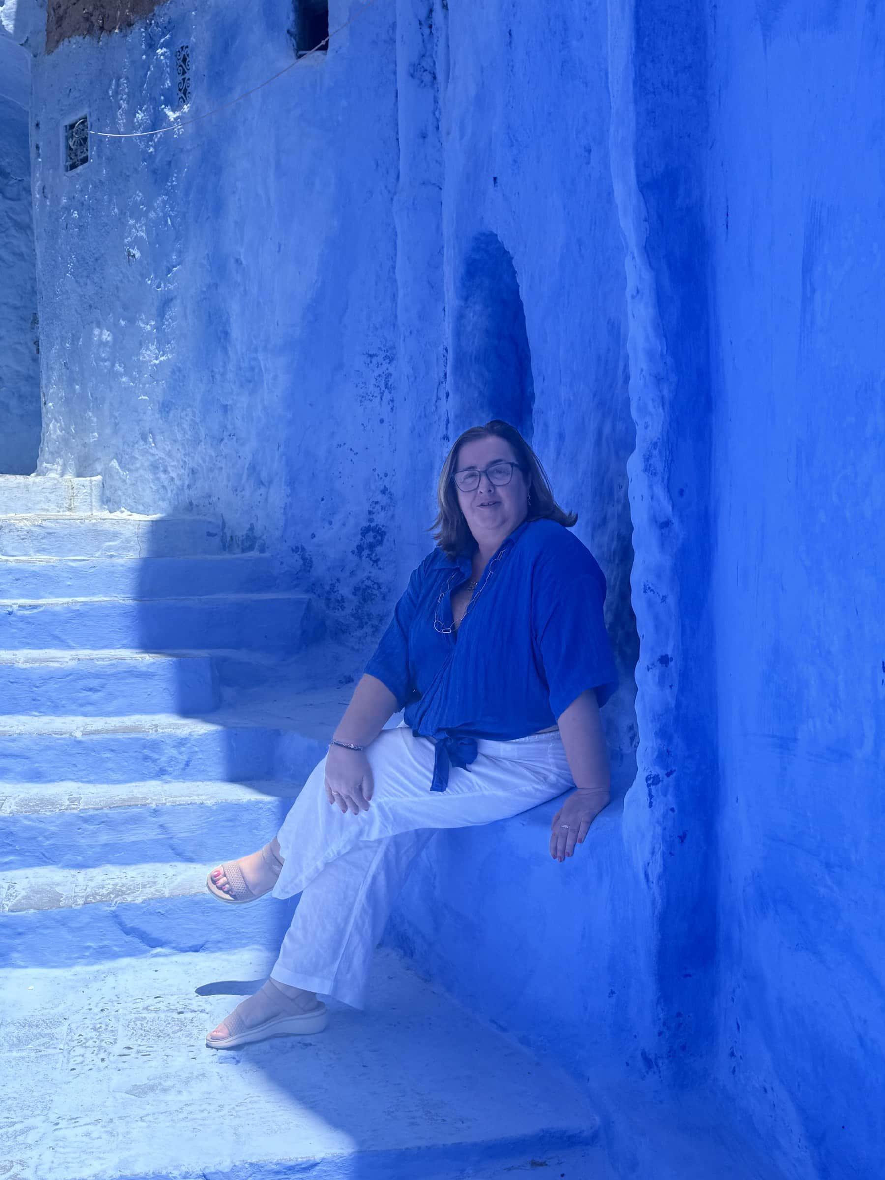 Viajera sentada en las escaleras azules de la medina de Chefchaouen, la ciudad azul de Marruecos