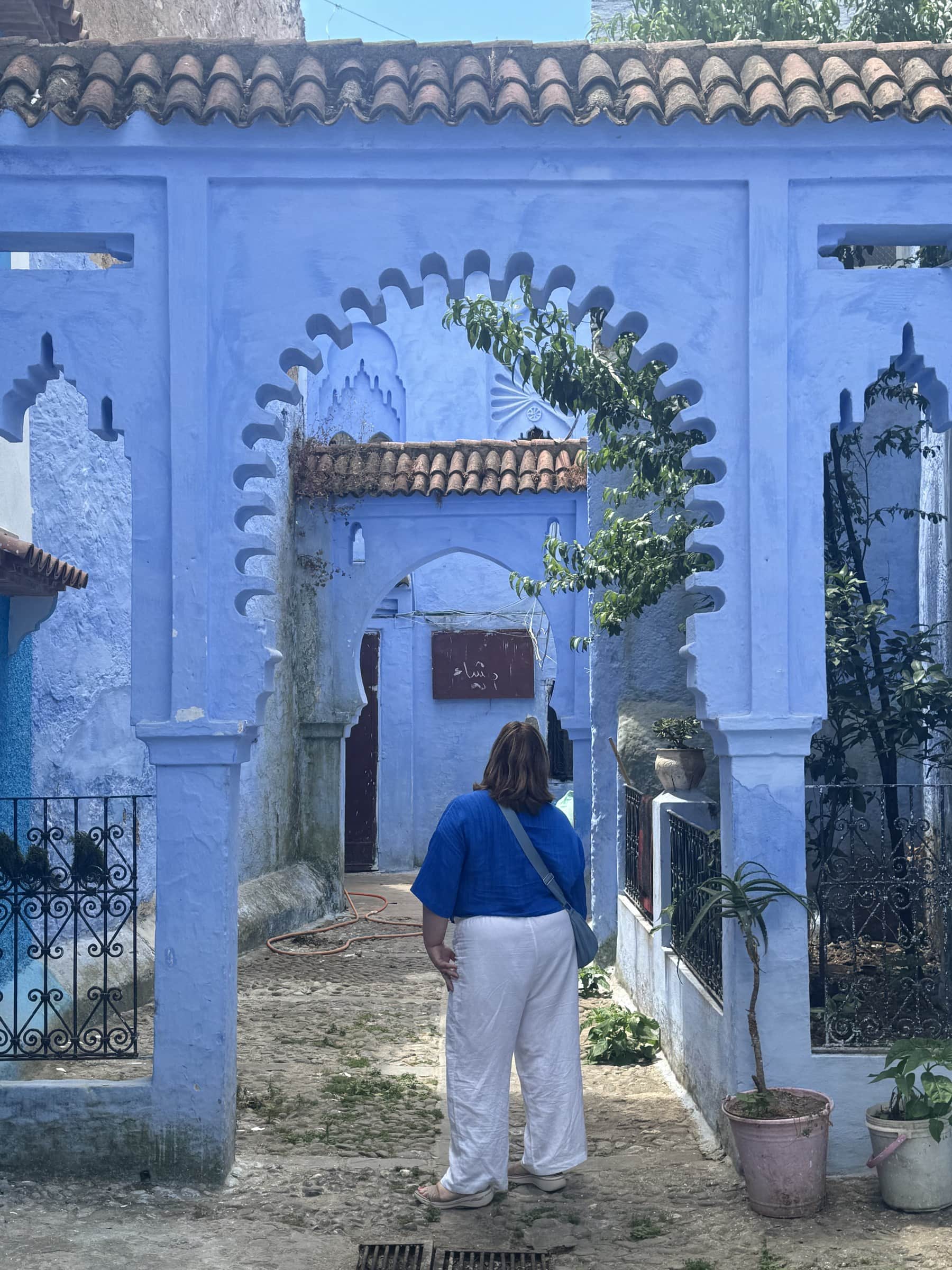 Viajera contemplando arco morisco azul en la medina de Chefchaouen, la ciudad azul de Marruecos