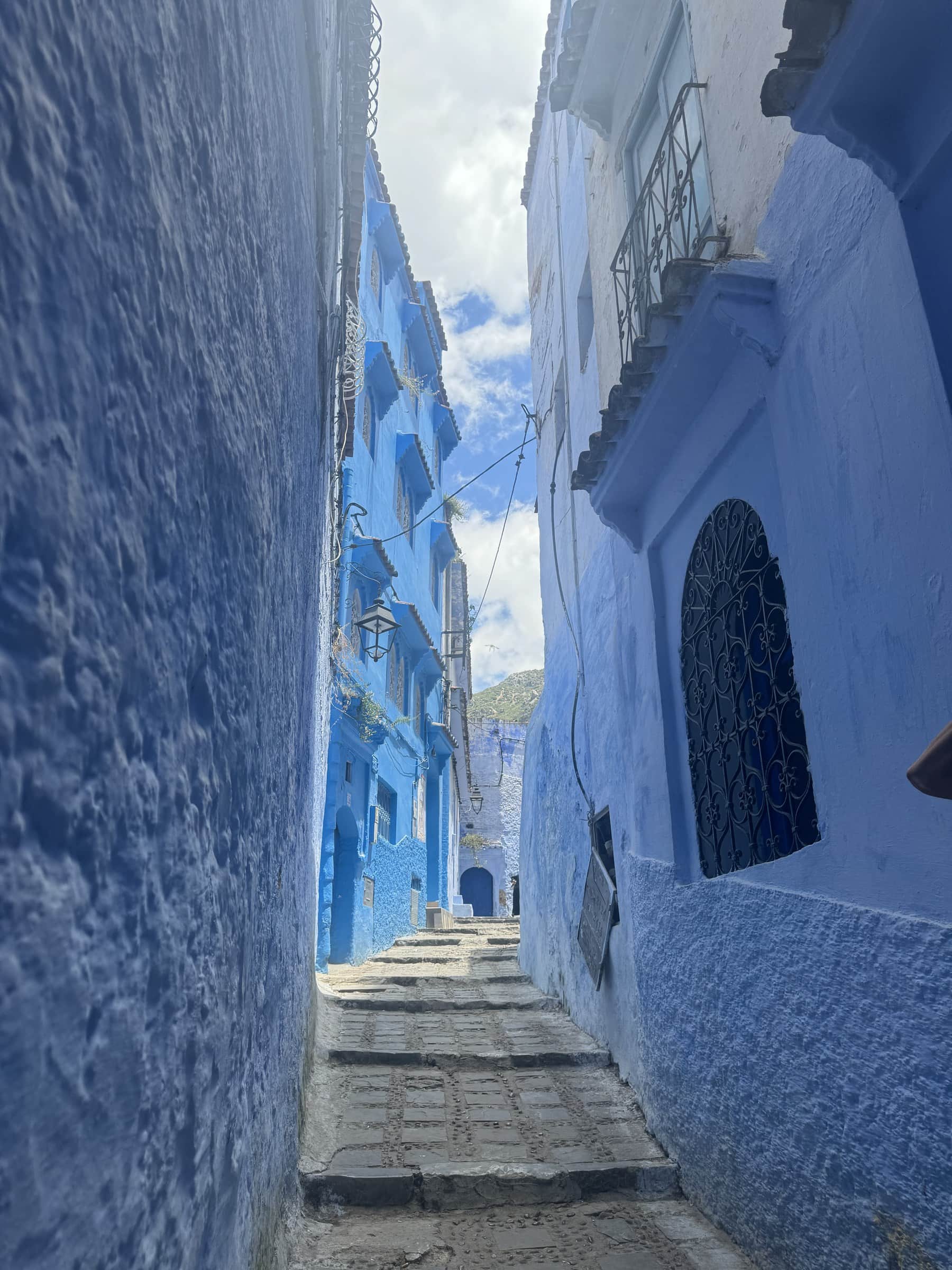 Callejón azul de Chefchaouen con escaleras de piedra y paredes pintadas de azul índigo, Marruecos