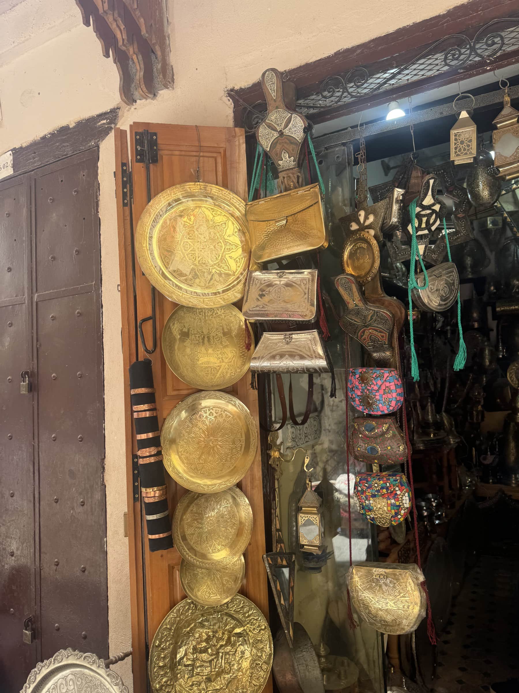 Tienda de artesanía en la medina de Marruecos con bandejas de latón grabadas y bolsos colgantes