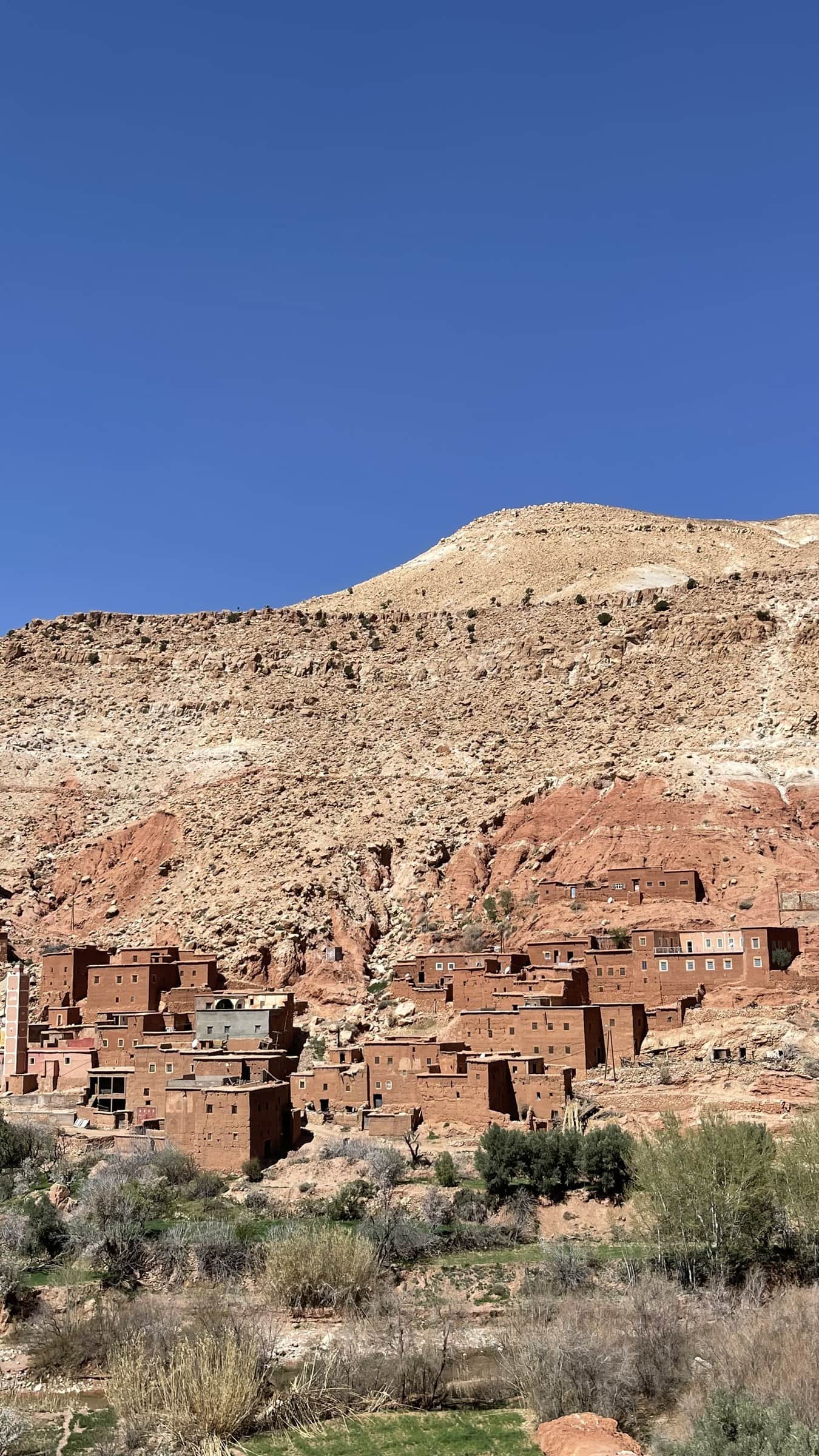 Aldea bereber de adobe rojo enclavada en las rocas del Valle del Dadés, Marruecos, bajo cielo azul intenso