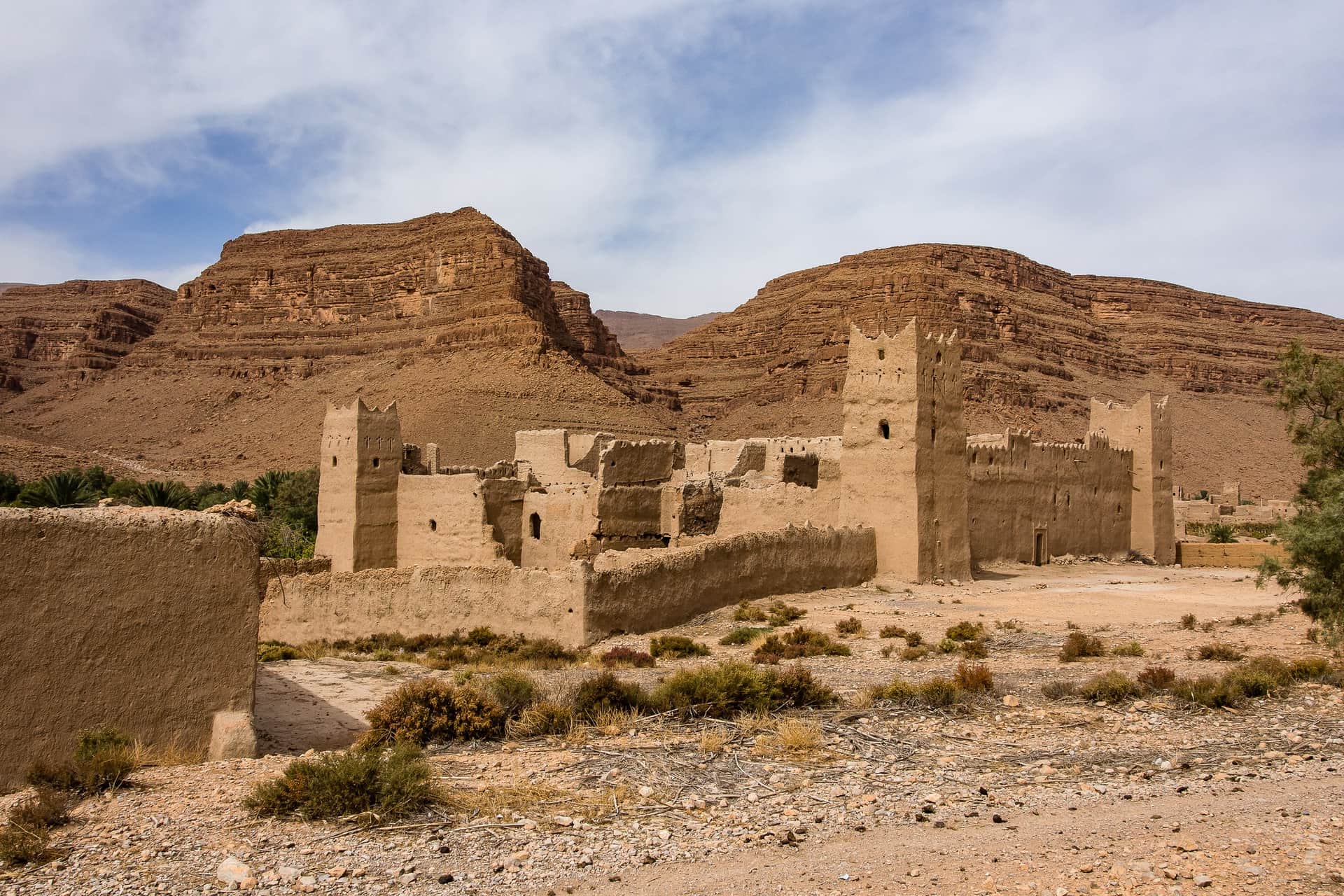 Kasbah de barro en ruinas en el Valle del Ziz, Marruecos, con imponentes acantilados rojizos al fondo