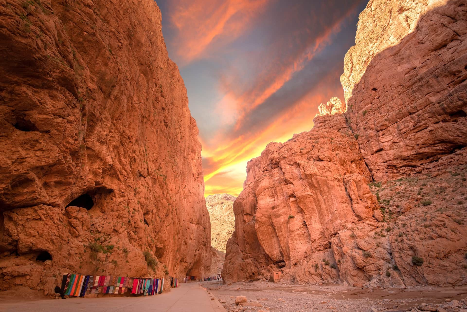 Gargantas del Todra al atardecer con paredes rojizas de 300 metros y puestos de telas bereberes, Marruecos