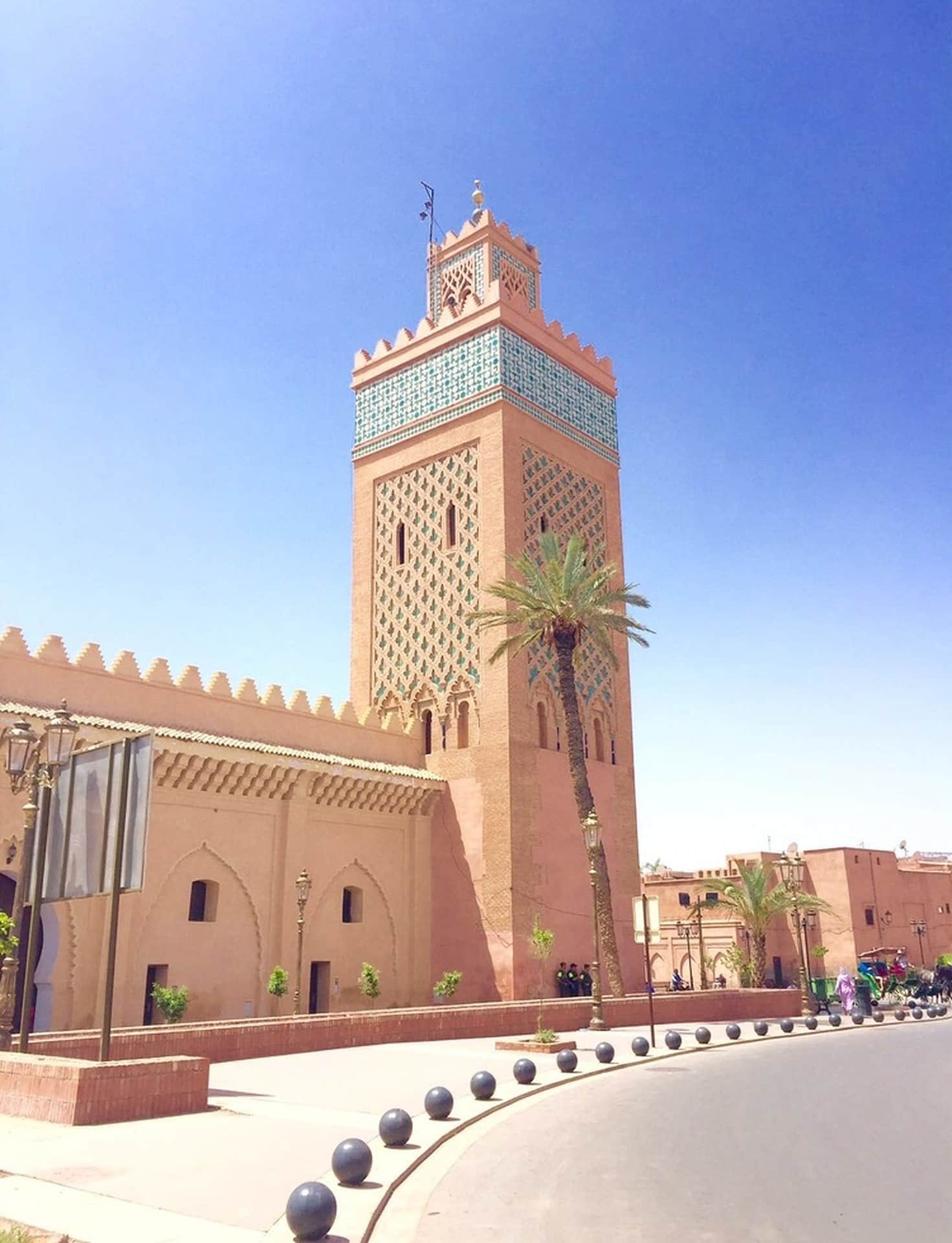 Minarete de la mezquita Koutoubia de Marrakech con palmeras bajo cielo azul despejado
