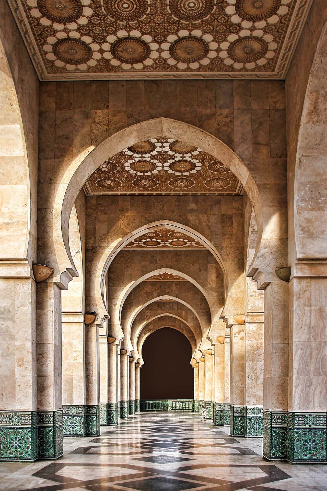 Arcos de mármol en perspectiva en la Mezquita Hassan II de Casablanca con techos de mosaicos dorados