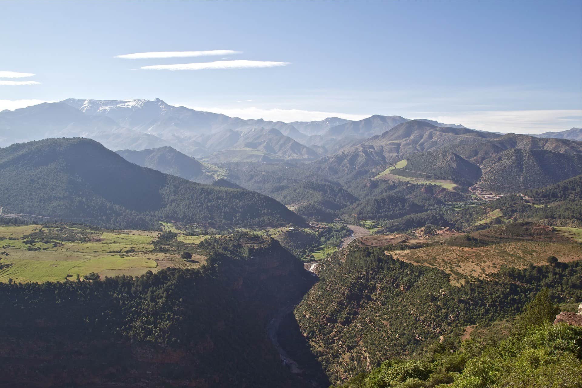Panorámica del Alto Atlas marroquí con valles verdes, bosques de cedros y cumbres nevadas al fondo