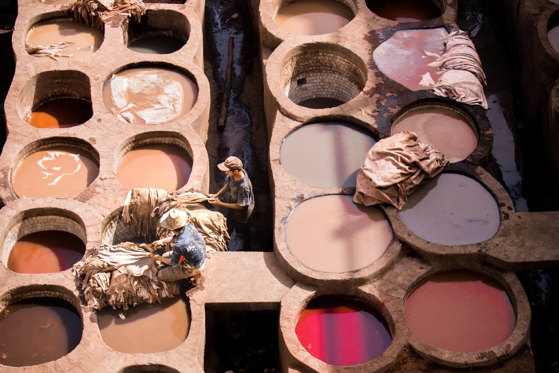 Trabajadores curtiendo pieles en las famosas tenerías de Chouara en Fez, con cubas de colores tierra y rosa