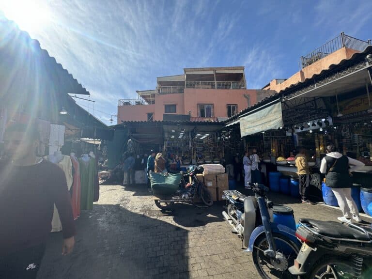 Bullicioso zoco de Marrakech con puestos de especias, ropa y motos en la medina de la ciudad roja