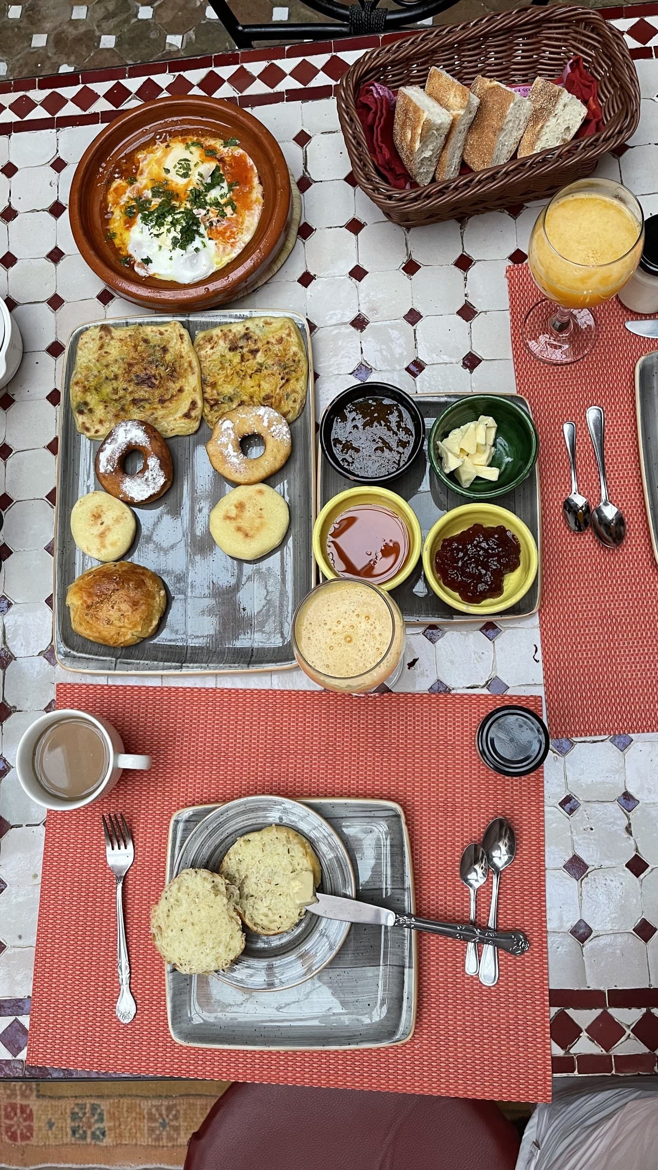 Desayuno marroquí tradicional en riad con msemen, beghrir, harcha, huevos en tajine, miel y zumo de naranja