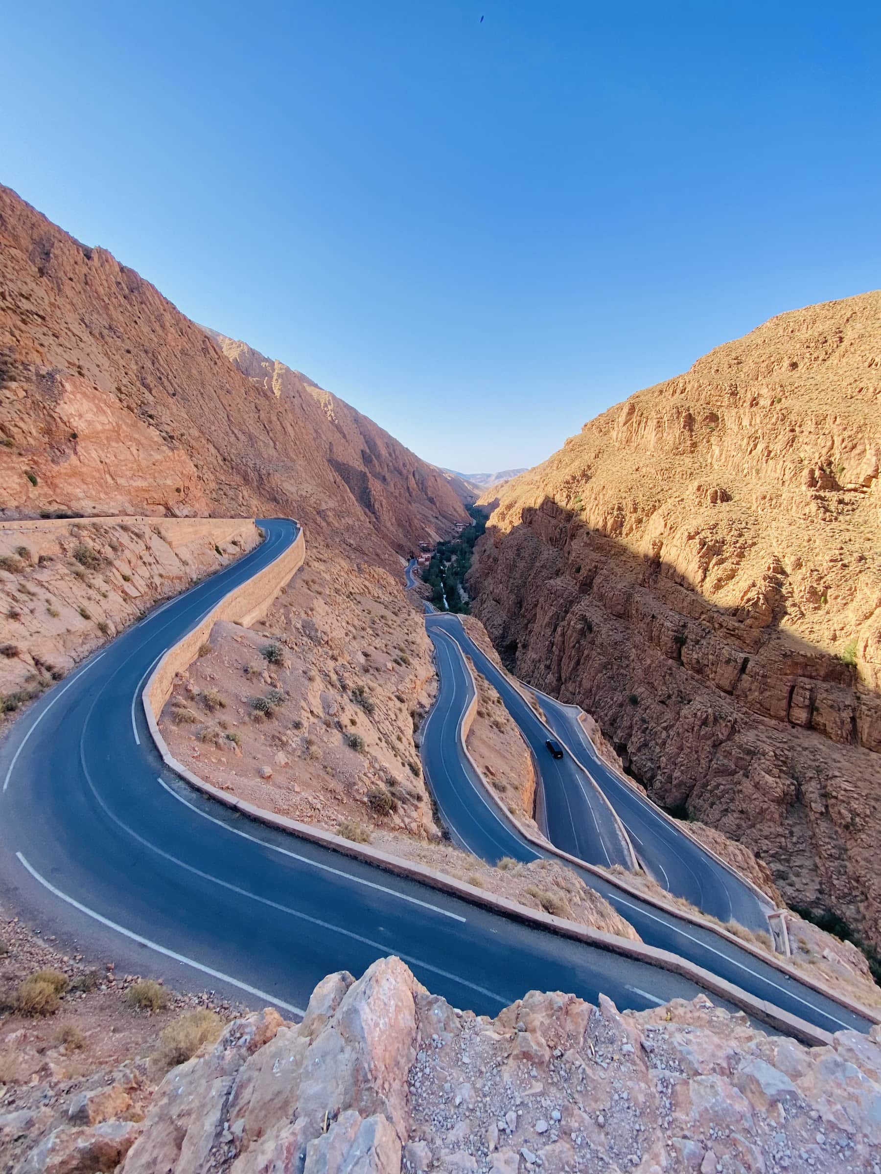 Carretera serpenteante entre las gargantas del Dadés con acantilados rojizos en Marruecos bajo cielo azul