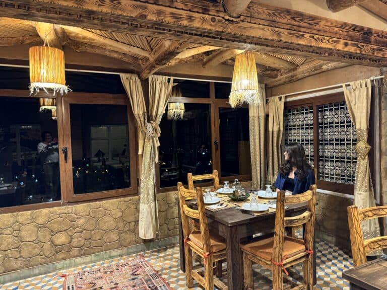 Cena nocturna en restaurante tradicional marroquí con vigas de madera, lámparas de esparto y suelo de zellige