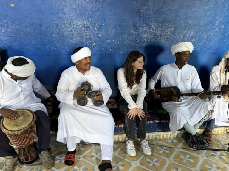 Viajera escuchando música Gnawa en Khamlia, Marruecos, junto a músicos con qraqeb y guembri