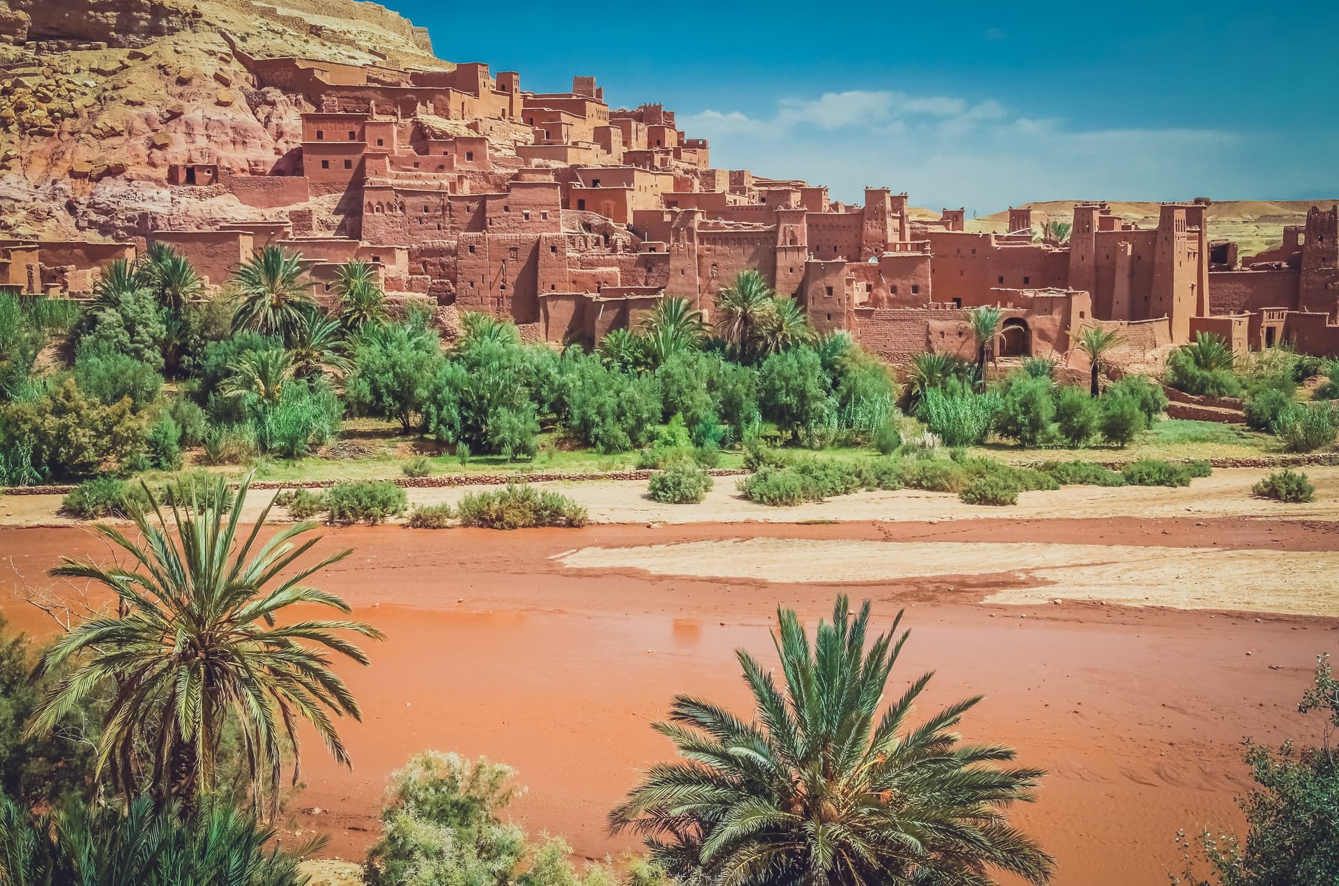 Kasbah de Ait Ben Haddou con sus torres de adobe rojo junto al río seco y palmeras, Patrimonio UNESCO de Marruecos