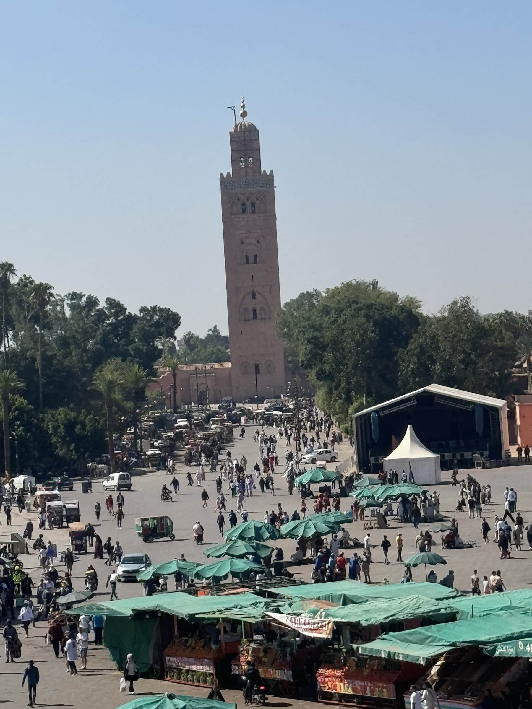 Plaza Jemaa el-Fna de Marrakech con la mezquita Koutoubia al fondo y puestos de mercado en primer plano
