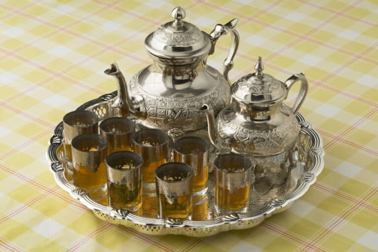 Servicio tradicional de té moruno marroquí con teteras de plata cincelada y vasos sobre bandeja plateada