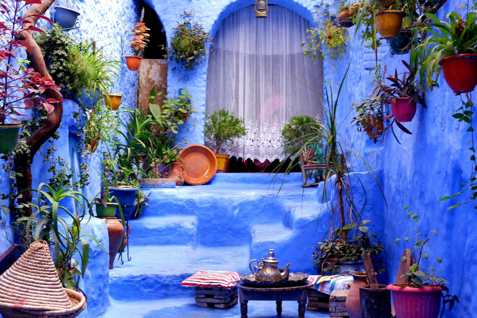 Rincón azul de Chefchaouen con macetas de colores, escaleras pintadas y tetera marroquí de plata