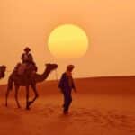 Viajeros recorriendo el desierto de Marruecos en camello al atardecer